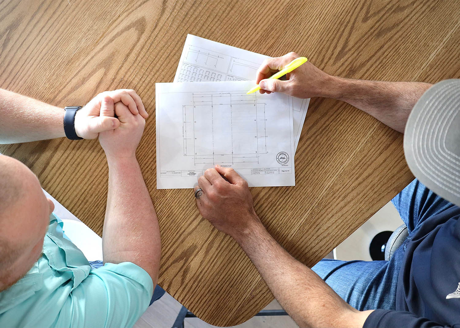 two employees of metal building detailing looking over designs on paper